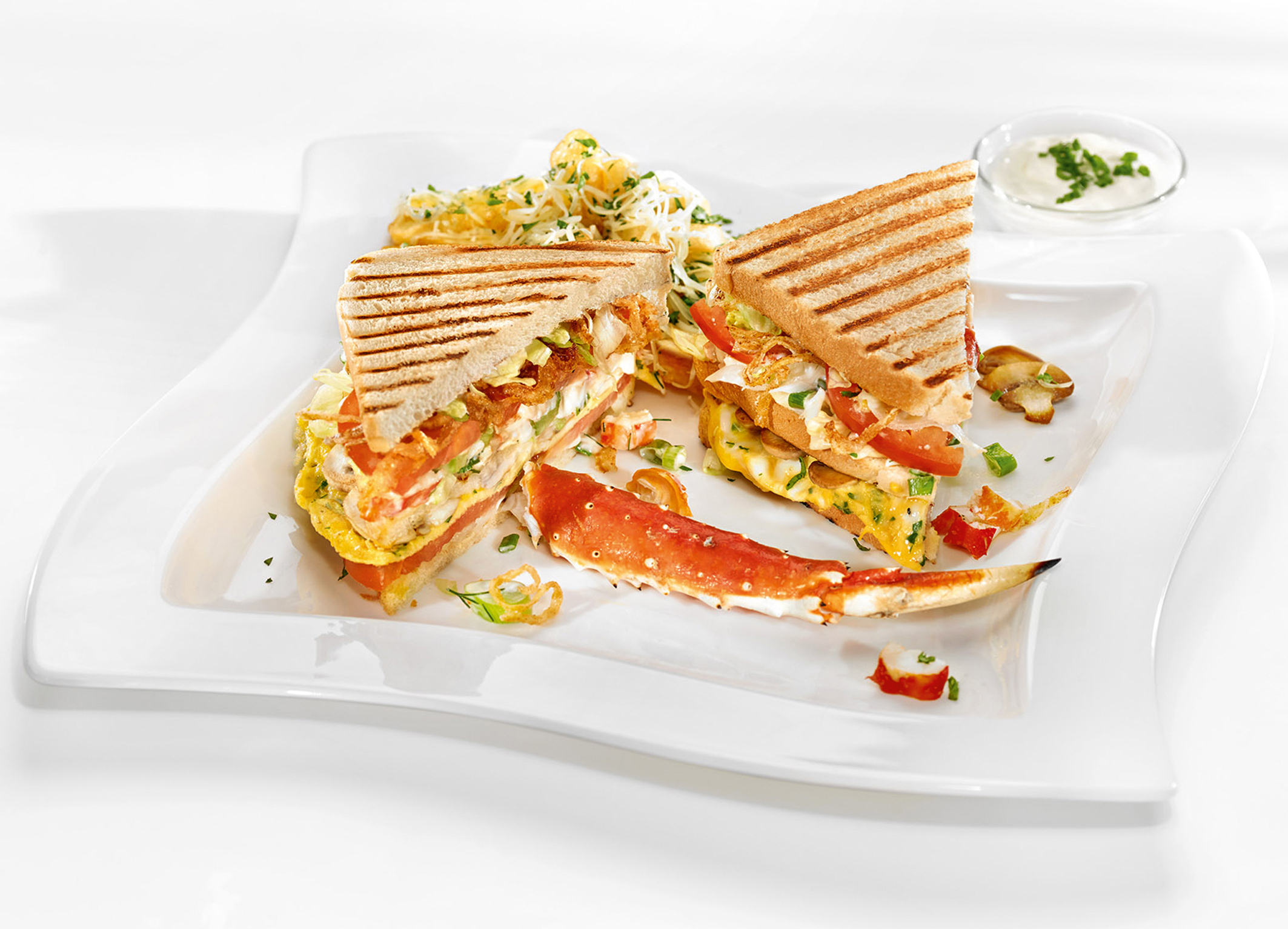 Club Sandwich „Nova Scotia“ auf Kräuterrührei und gebratenen Champignons, serviert mit Käse-Kartoffelsticks