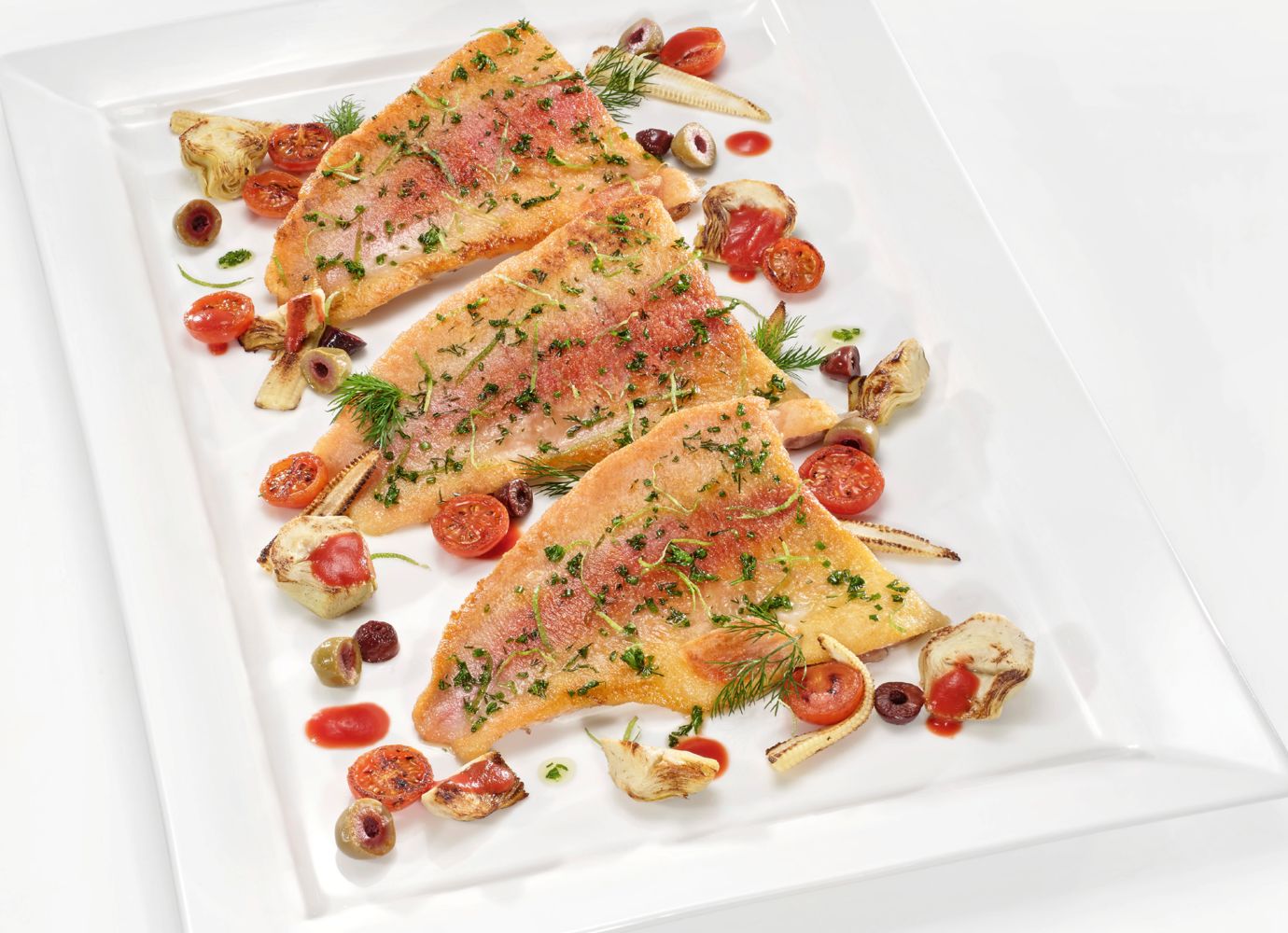 Das Goldforellenfilet wird mit Artischocken, Tomaten, Maiskölbchen und Oliven serviert. Foto: Landzeit