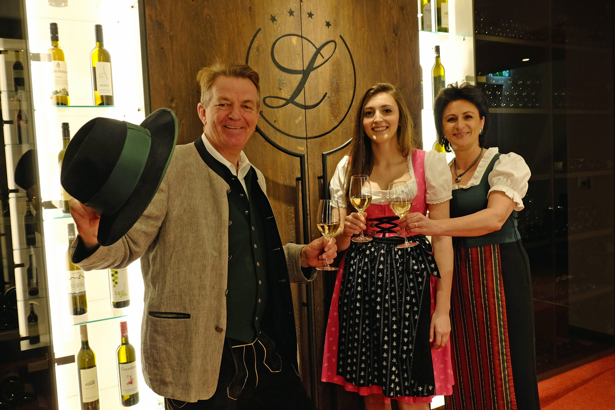 Ernst und Andrea Legenstein mit Tochter Laura stoßen vor dem Weintresor auf die Neueröffnung des Vulkanlandhotels Legenstein an. Foto: Vulkanhotel Legenstein/K. Wagner (frei)